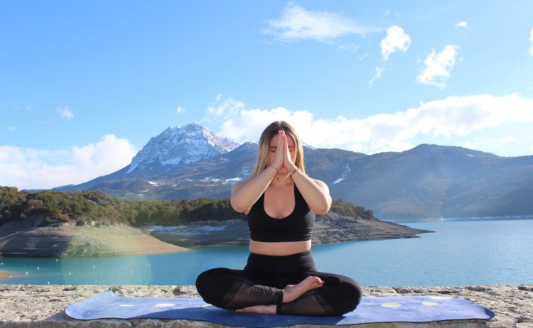 professeur de yoga qui pratique une position devant un lac